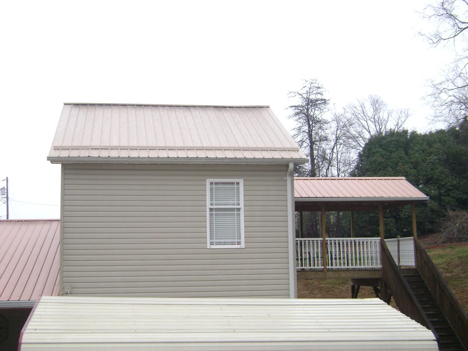 Tan metal roofs on a two story addition and attached porch, from a Roof Replacement job in Courtland